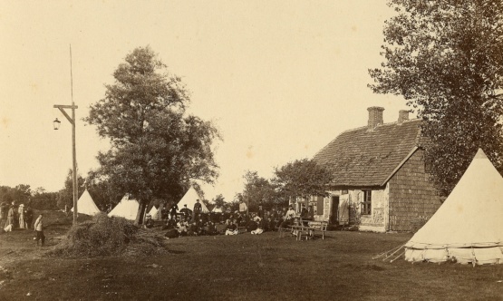 Foto des Zeltlages und eines Fachwerkhauses (zweifarbig in Sepia-Färbung)